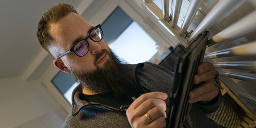 Ein Mann mit einer Brille der ein Tablet bedient