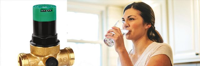 Ein Druckminderer Pb Frei, rechts im Bild ist eine Frau in der Küche und Trinkt ein Glas Wasser